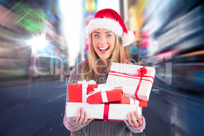 Composite image of festive blonde holding pile of gifts