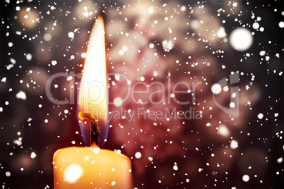Snow falling against candle burning