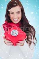 Composite image of happy brunette holding red gift with a bow