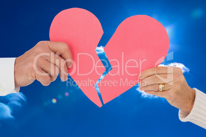 Composite image of couple holding a broken paper heart