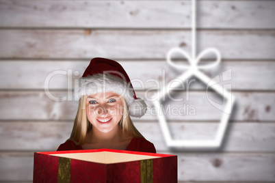 Composite image of festive blonde holding a gift