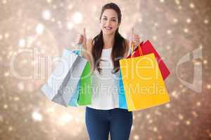 Composite image of happy brunette holding bags with thumbs up