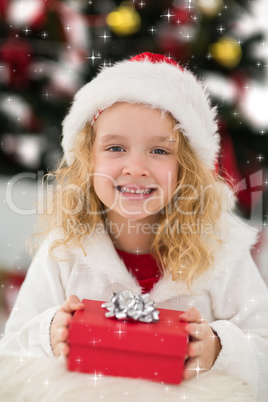 Composite image of festive little girl holding a gift