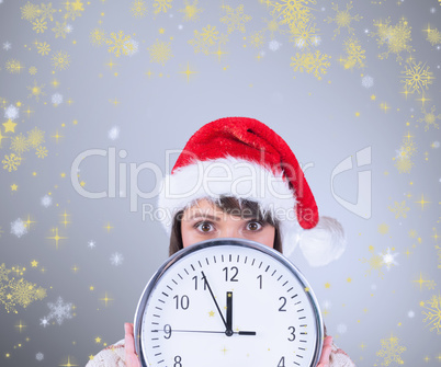 Composite image of festive brunette holding a clock