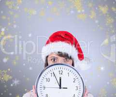 Composite image of festive brunette holding a clock