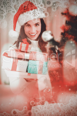 Composite image of festive brunette holding pile of gifts near a