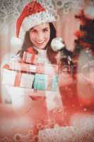 Composite image of festive brunette holding pile of gifts near a