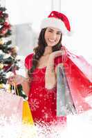 Composite image of smiling brunette in red dress holding shopping bags