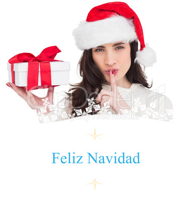 Composite image of festive brunette holding gift and keeping a s