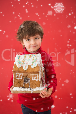 Composite image of festive little boy holding gingerbread house