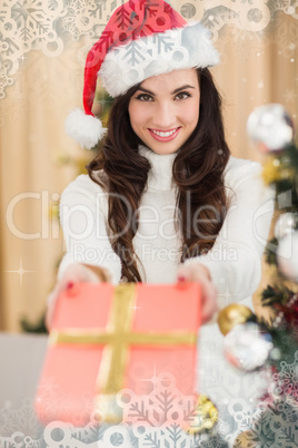 Composite image of surprised brunette showing a gift