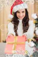Composite image of surprised brunette showing a gift
