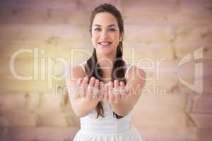 Composite image of smiling brunette holding hands out