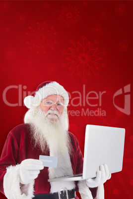 Composite image of santa pays with credit card on a laptop