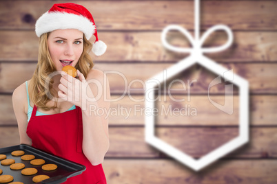 Composite image of festive blonde eating hot cookies