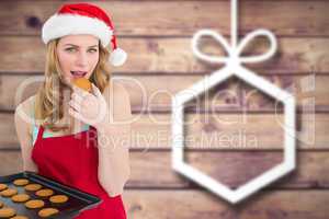 Composite image of festive blonde eating hot cookies