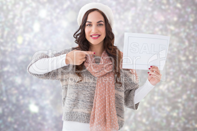 Composite image of brunette in winter clothes showing sale sign