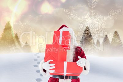 Composite image of santa carrying gifts in the snow