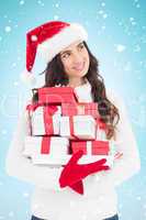 Composite image of joyful brunette in santa hat and red gloves h