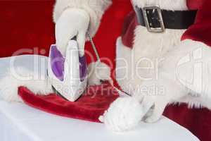 Composite image of father christmas is ironing his hat