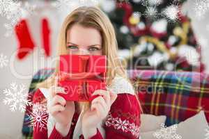 Composite image of young woman hiding behind a gift