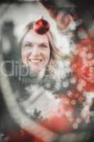 Composite image of festive blonde hanging bauble on christmas tr