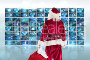 Composite image of santa carrying sack of gifts