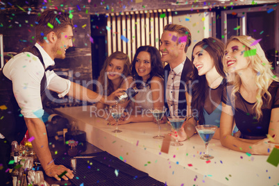 Composite image of attractive friends drinking cocktails togethe