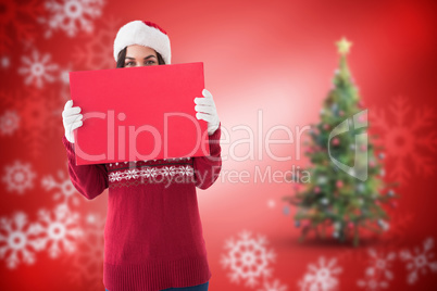 Composite image of brunette in winter clothes holding sign