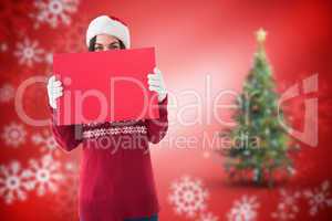 Composite image of brunette in winter clothes holding sign