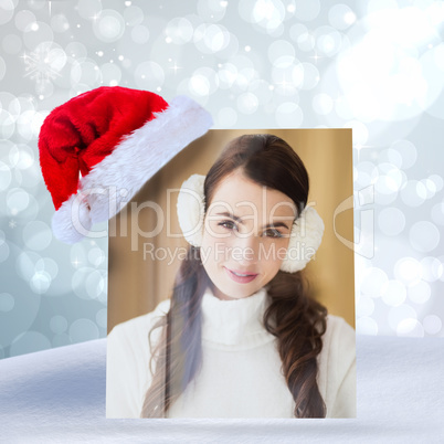 Composite image of pretty brunette with ear muffs smiling at cam