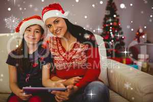 Composite image of festive mother and daughter using tablet