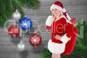 Composite image of festive blonde carrying sack of presents