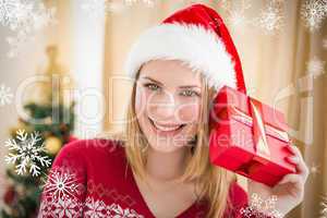 Composite image of festive blonde holding a gift