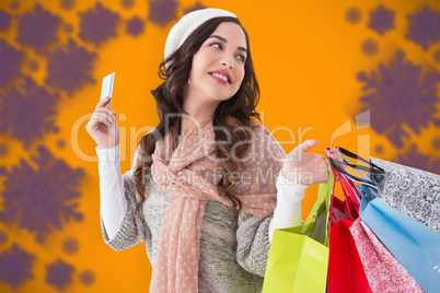 Composite image of beauty brunette holding credit card and shopp