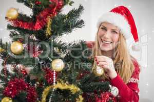 Composite image of smiling woman hanging christmas decorations o