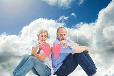 Composite image of sad mature couple holding a broken heart