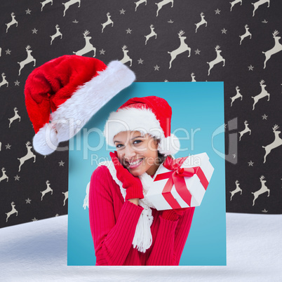 Composite image of festive brunette holding gift