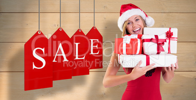 Composite image of festive blonde holding pile of gifts