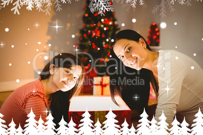 Composite image of festive mother and daughter opening a glowing