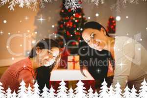 Composite image of festive mother and daughter opening a glowing