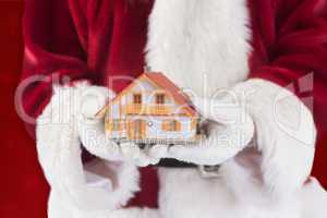 Composite image of santa holds a tiny house in his hands