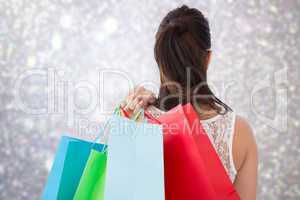 Composite image of rear view of brunette holding shopping bags
