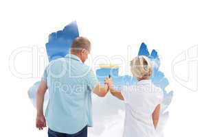 Composite image of happy older couple painting a sky