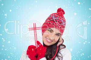 Composite image of festive brunette in winter clothes pointing g
