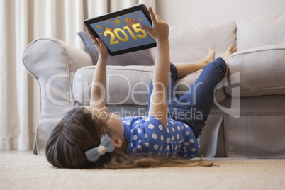 Composite image of little girl using digital tablet in the livin