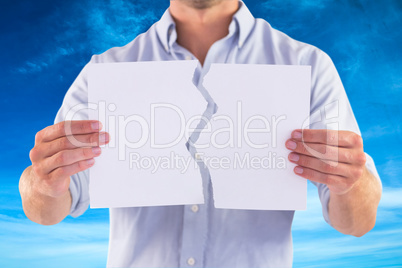 Composite image of man holding torn white paper
