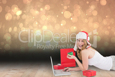 Composite image of happy woman shopping online lying on the floo