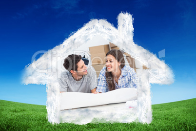 Composite image of couple lying on the floor and holding house p
