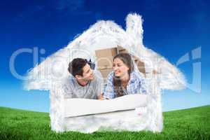 Composite image of couple lying on the floor and holding house p